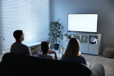 Photo of Happy family watching tv together at home, back view