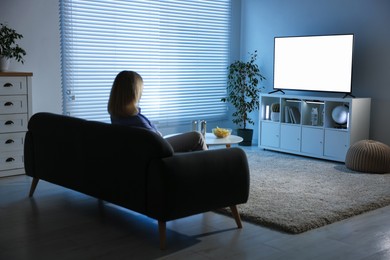 Woman watching tv on couch at home