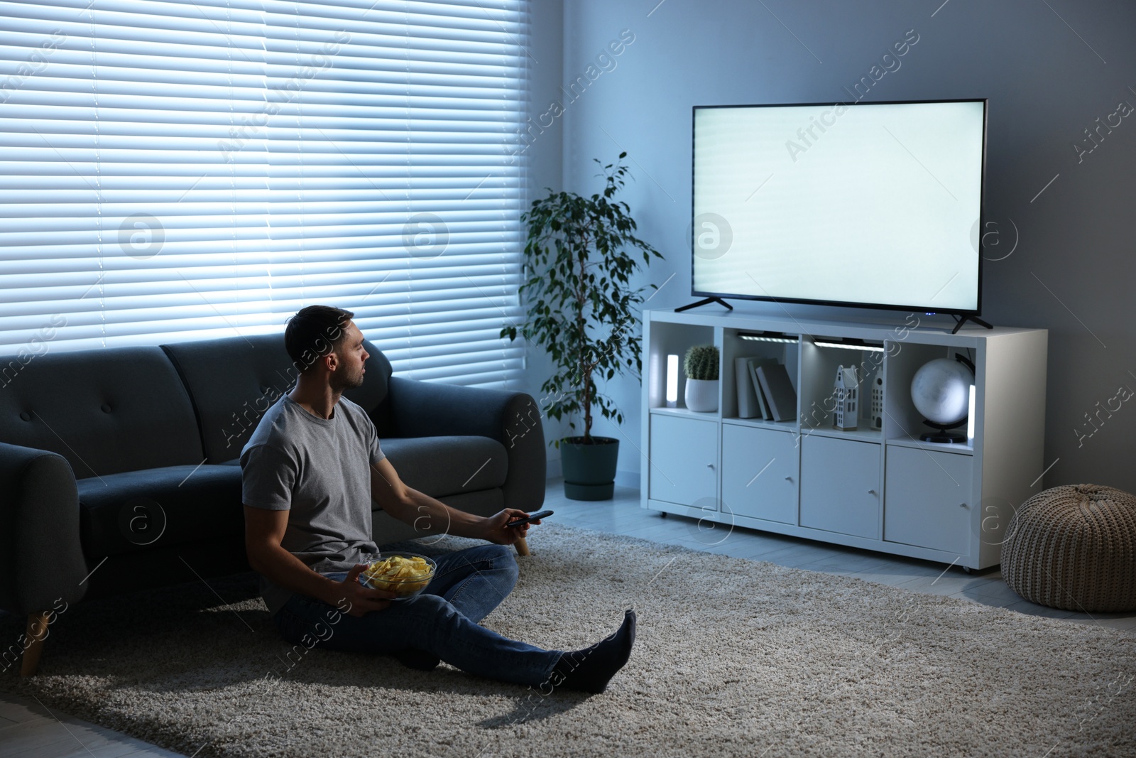 Photo of Man with chips watching tv at home