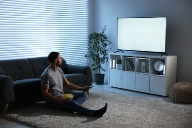 Man with chips watching tv at home