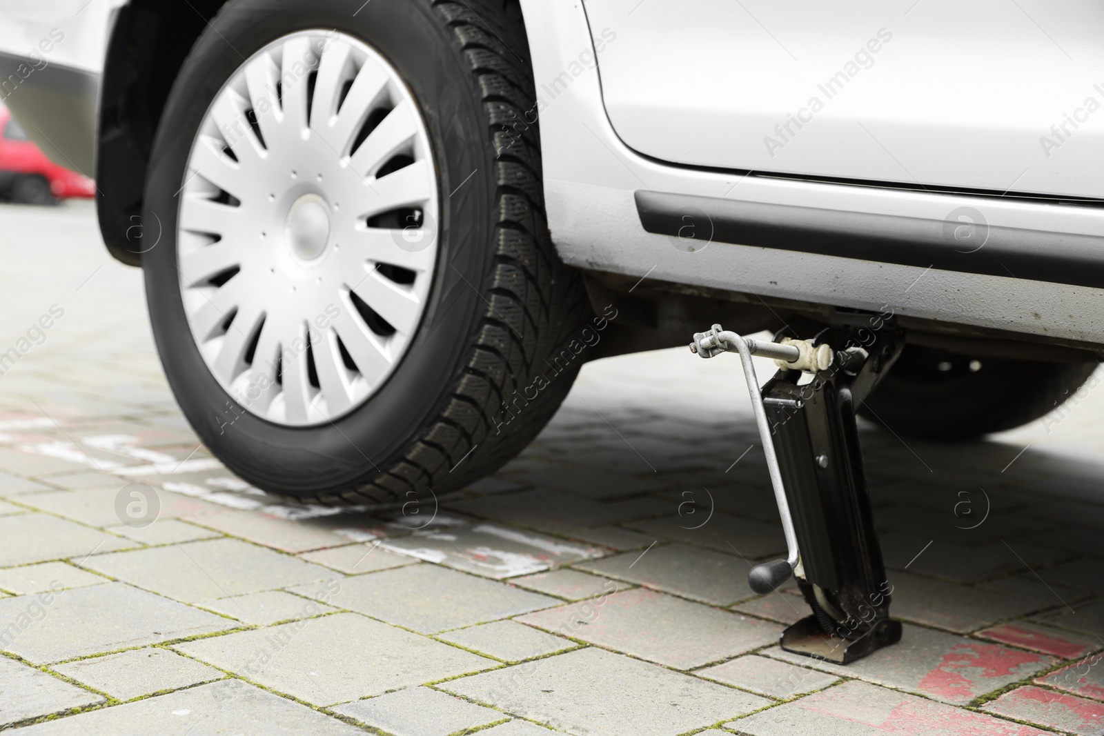 Photo of Car lifted by scissor jack on roadside outdoors