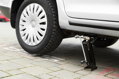 Photo of Car lifted by scissor jack on roadside outdoors