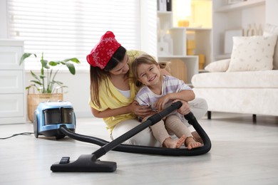 Photo of Little helper. Daughter and mother vacuuming together at home