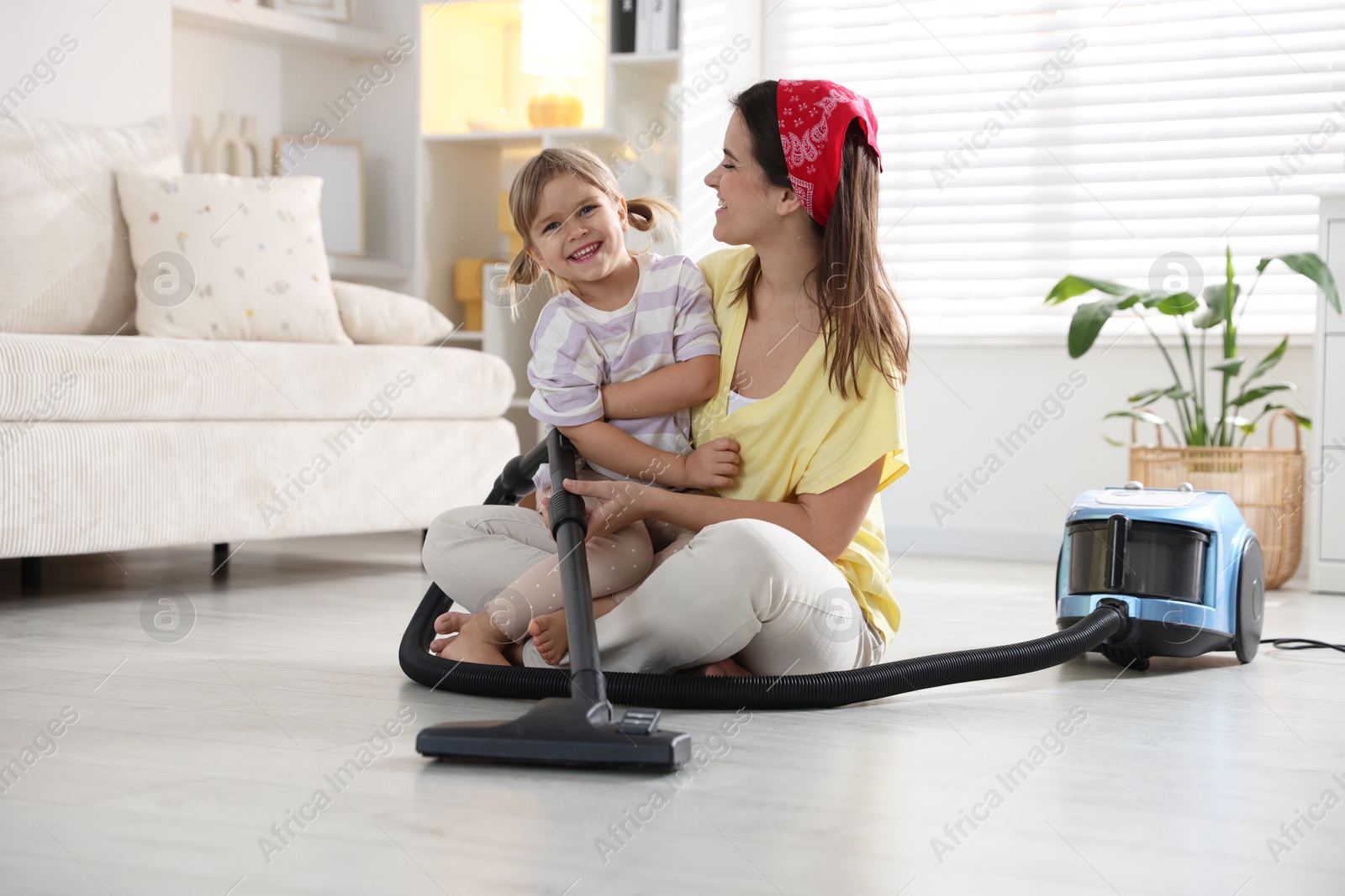 Photo of Little helper. Daughter and mother vacuuming together at home