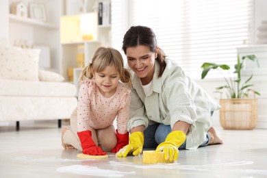 Little helper. Daughter and mother cleaning floor together at home