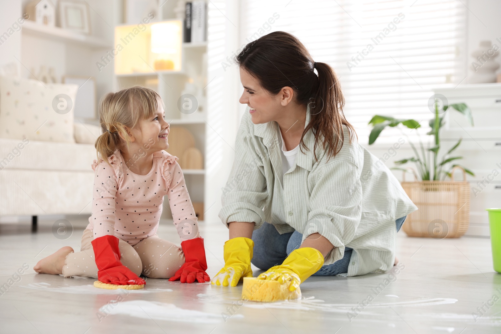 Photo of Little helper. Daughter and mother cleaning floor together at home