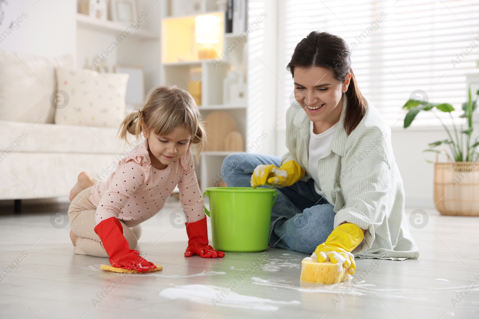 Photo of Little helper. Daughter and mother cleaning floor together at home