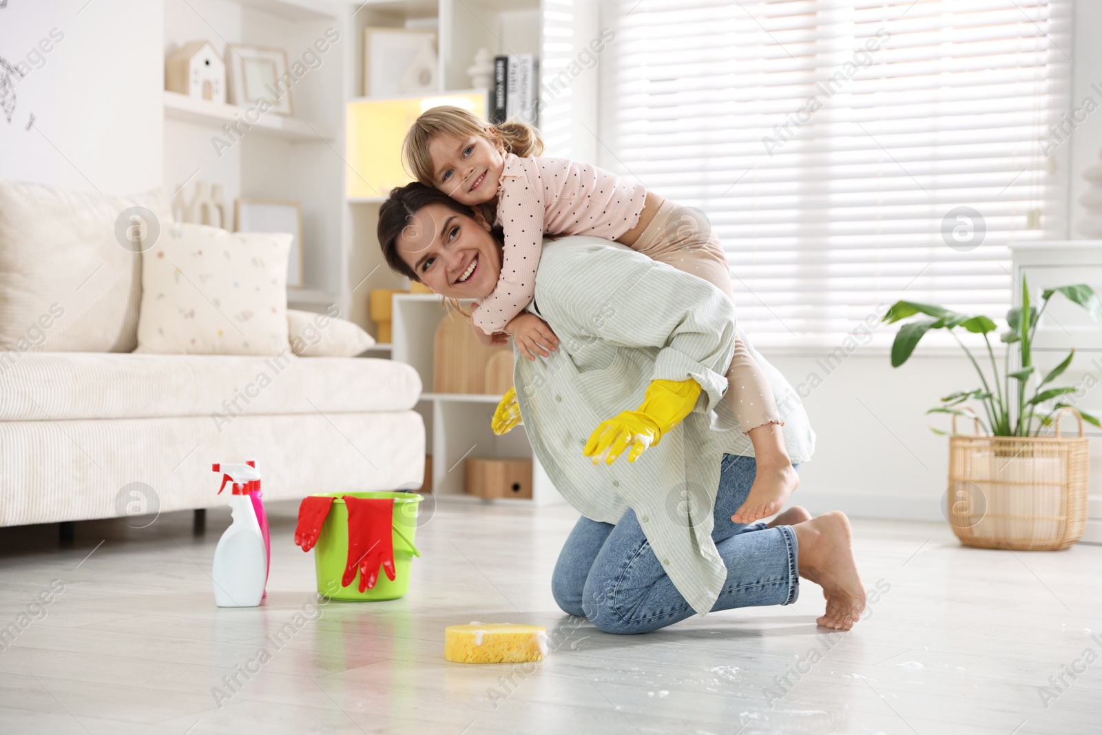 Photo of Little helper. Cute girl and her mother having fun while cleaning floor at home