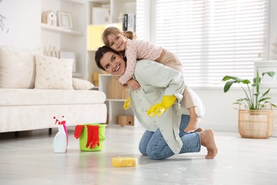 Little helper. Cute girl and her mother having fun while cleaning floor at home