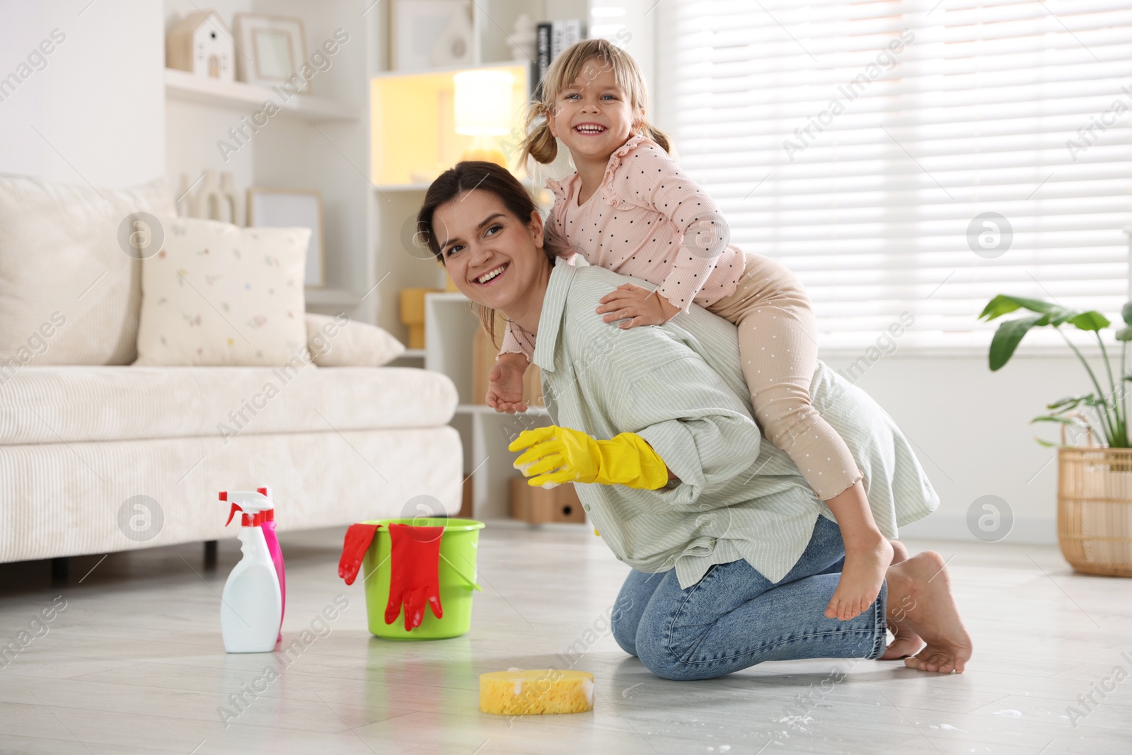 Photo of Little helper. Cute girl and her mother having fun while cleaning floor at home