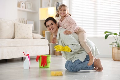 Little helper. Cute girl and her mother having fun while cleaning floor at home