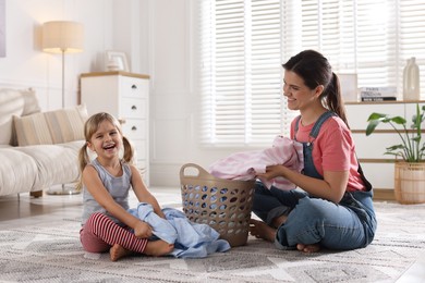 Photo of Little helper. Daughter and her mother with laundry at home