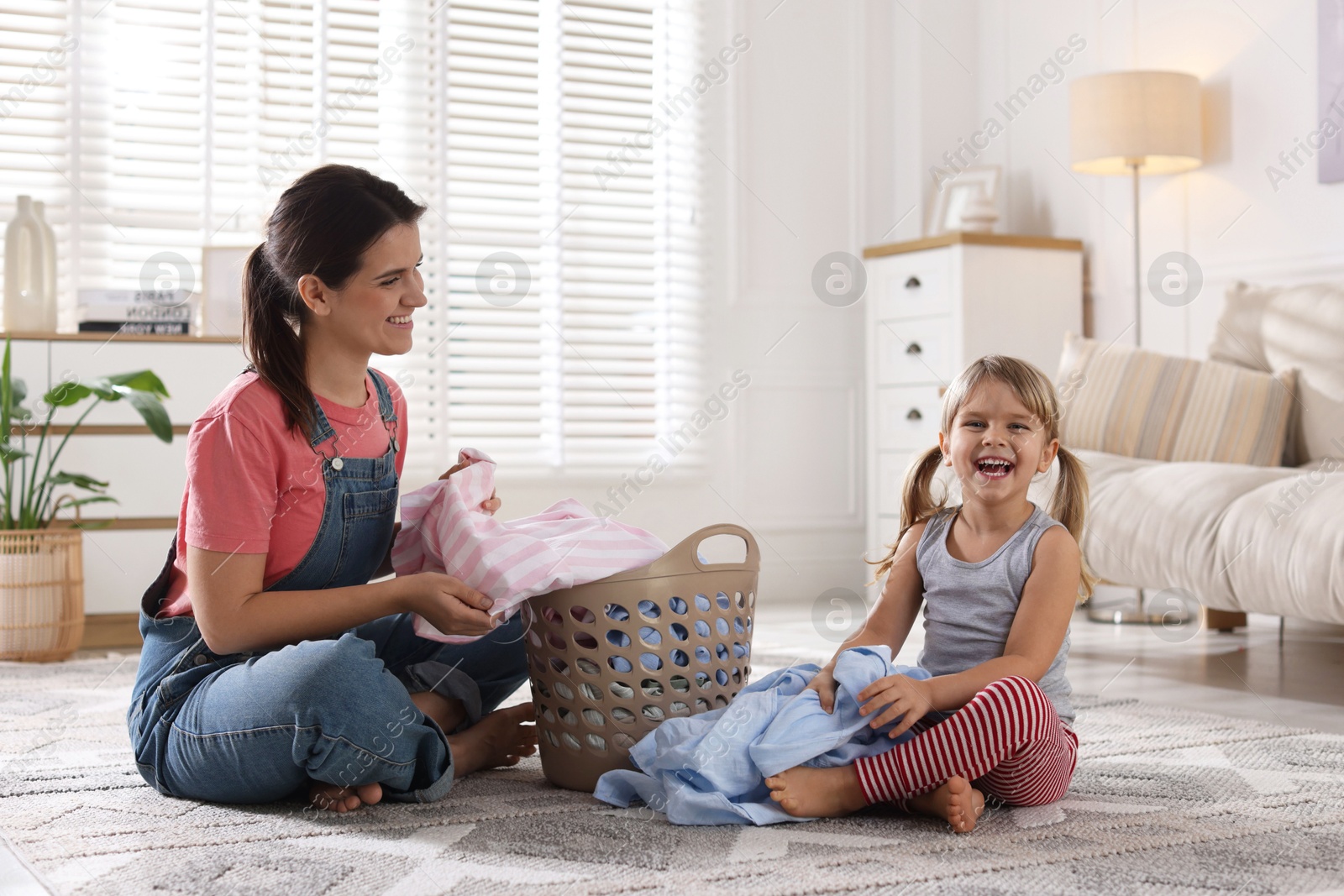 Photo of Little helper. Daughter and her mother with laundry at home