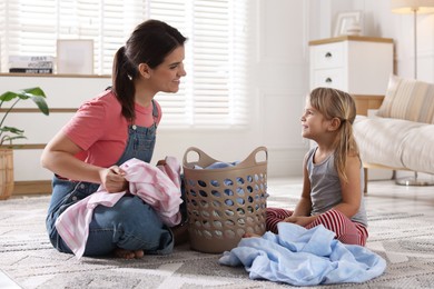 Photo of Little helper. Daughter and her mother with laundry at home