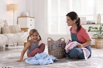 Little helper. Daughter and her mother with laundry at home