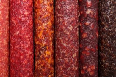 Different tasty smoked sausages as background, top view