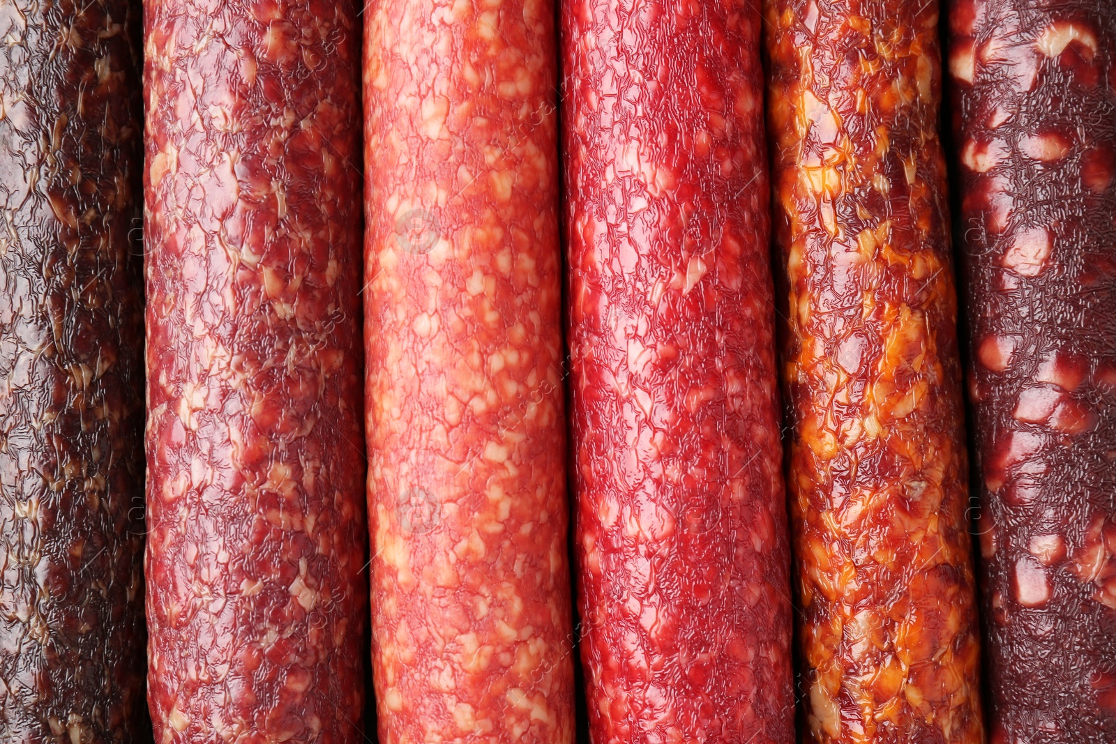 Photo of Different tasty smoked sausages as background, top view