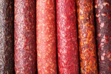 Different tasty smoked sausages as background, top view