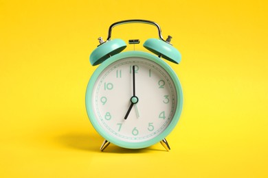 Photo of One turquoise alarm clock on yellow background