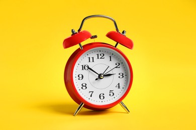 Photo of One red alarm clock on yellow background