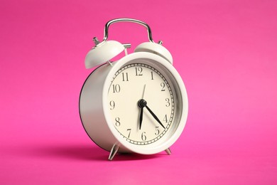 Photo of One white alarm clock on bright pink background