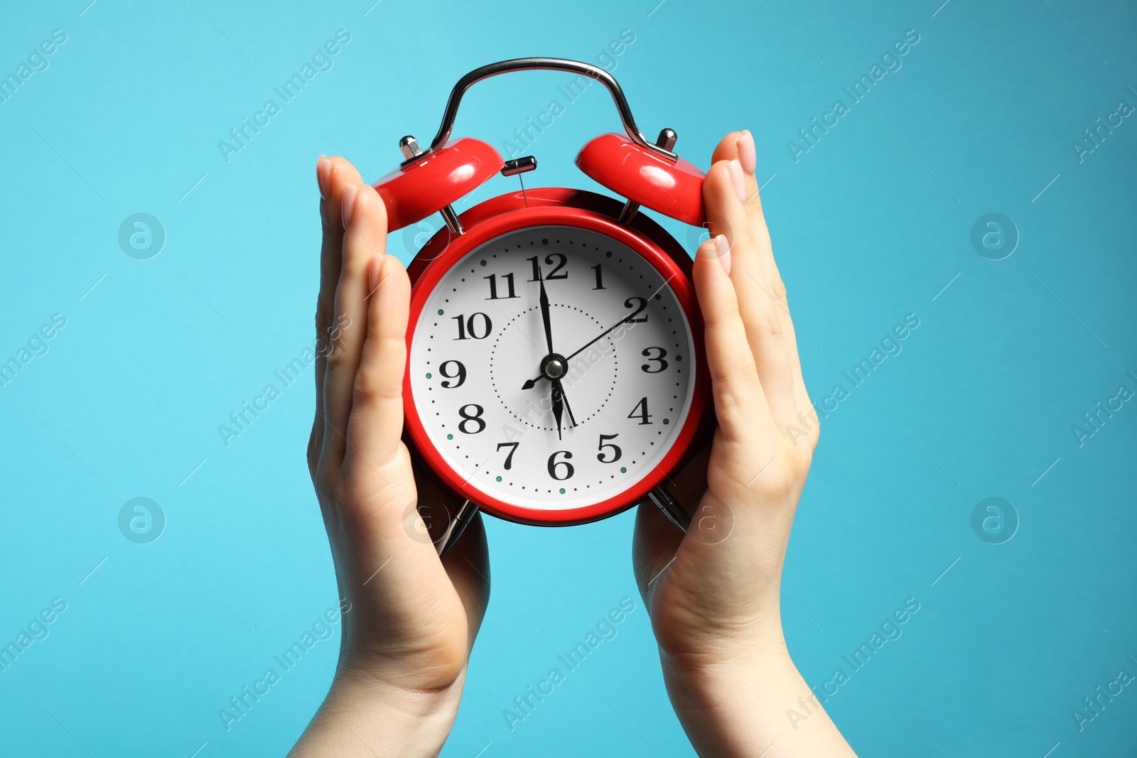 Woman with red alarm clock on light blue background, closeup Photo of Woman with red alarm clock on light blue background, closeup