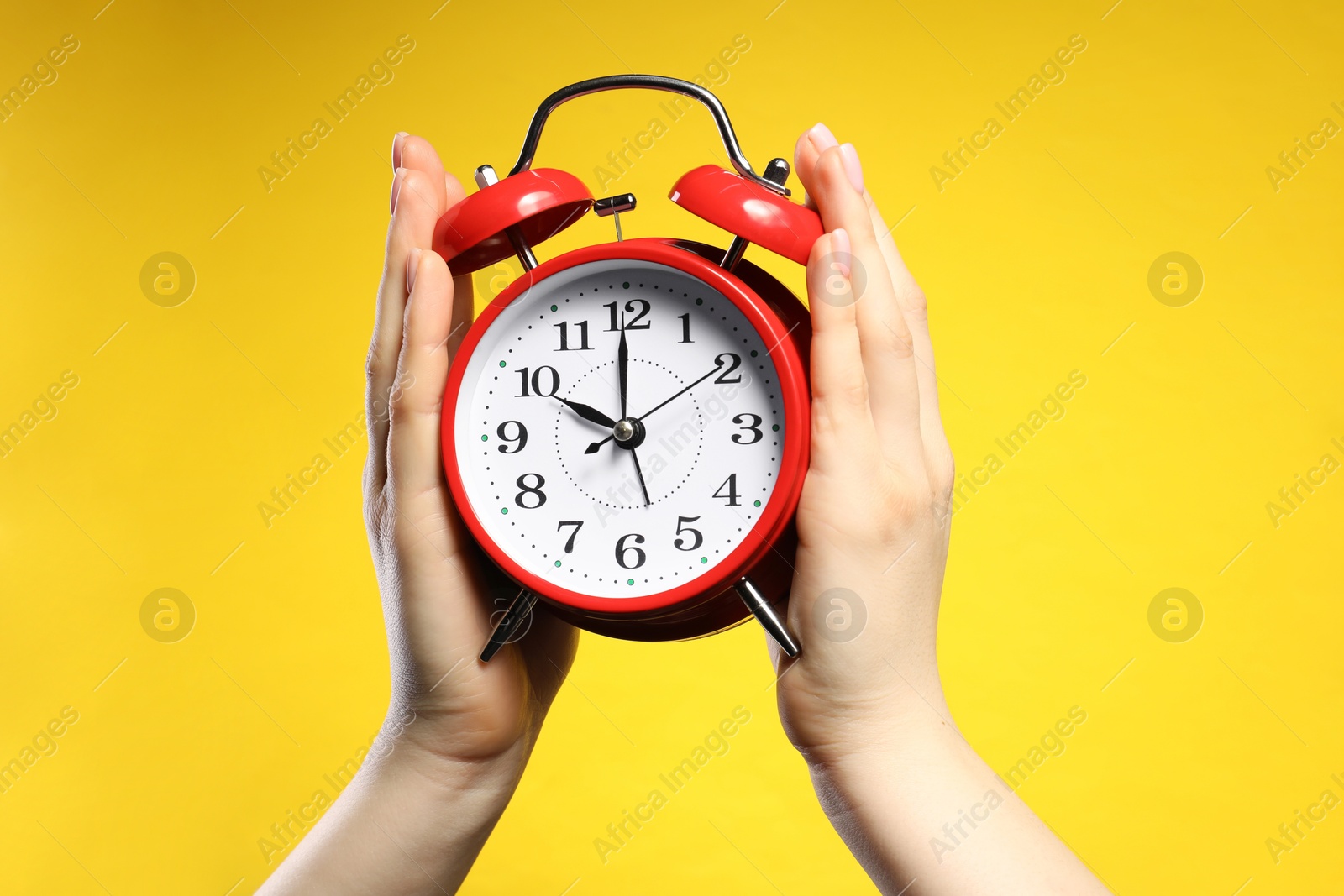 Woman with red alarm clock on yellow background, closeup Photo of Woman with red alarm clock on yellow background, closeup