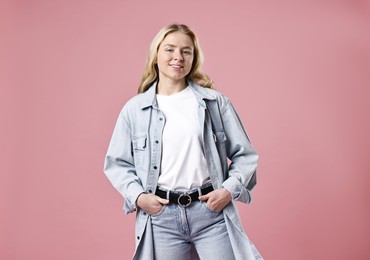 Smiling woman in stylish jeans on pink background