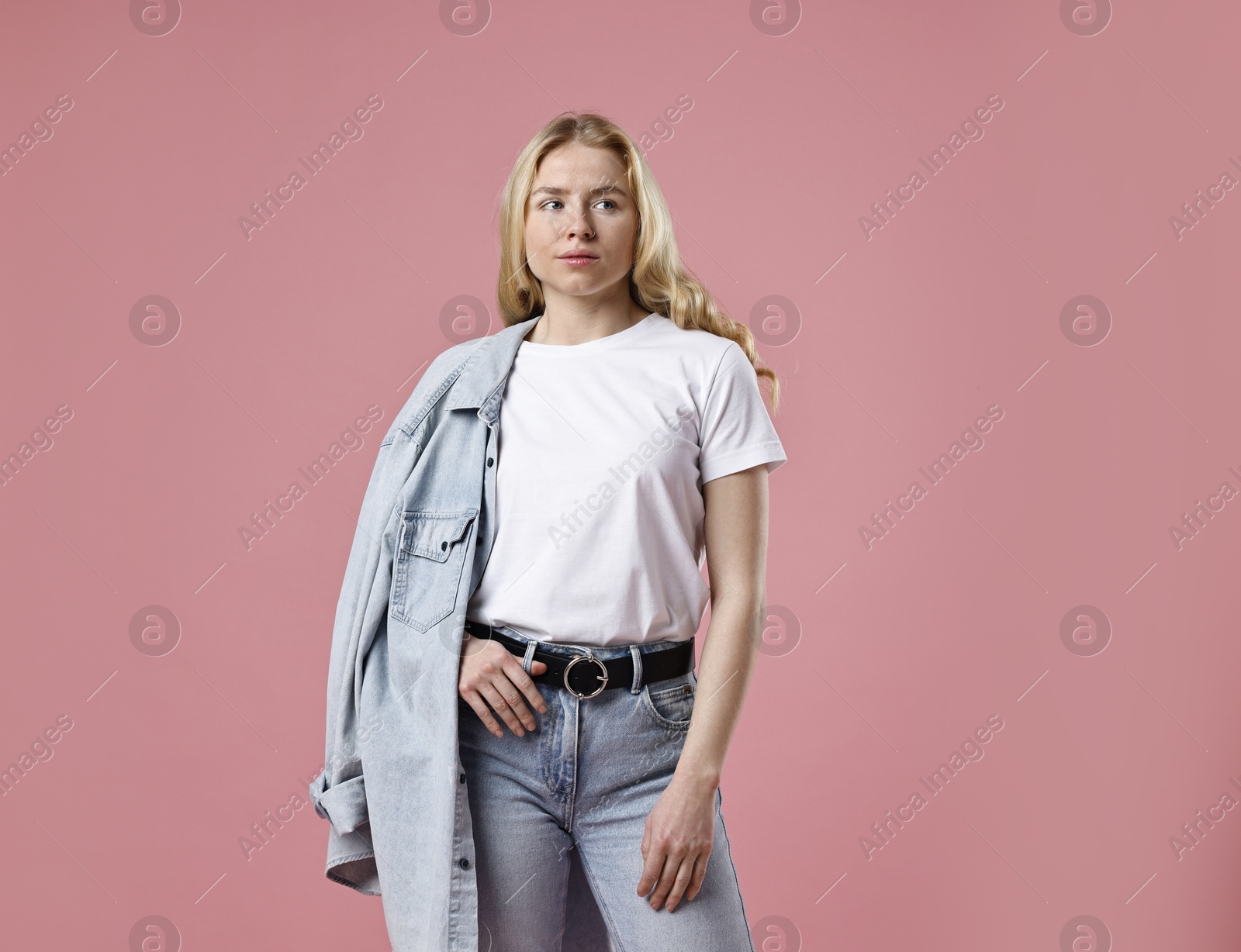 Photo of Beautiful young woman in stylish jeans on pink background