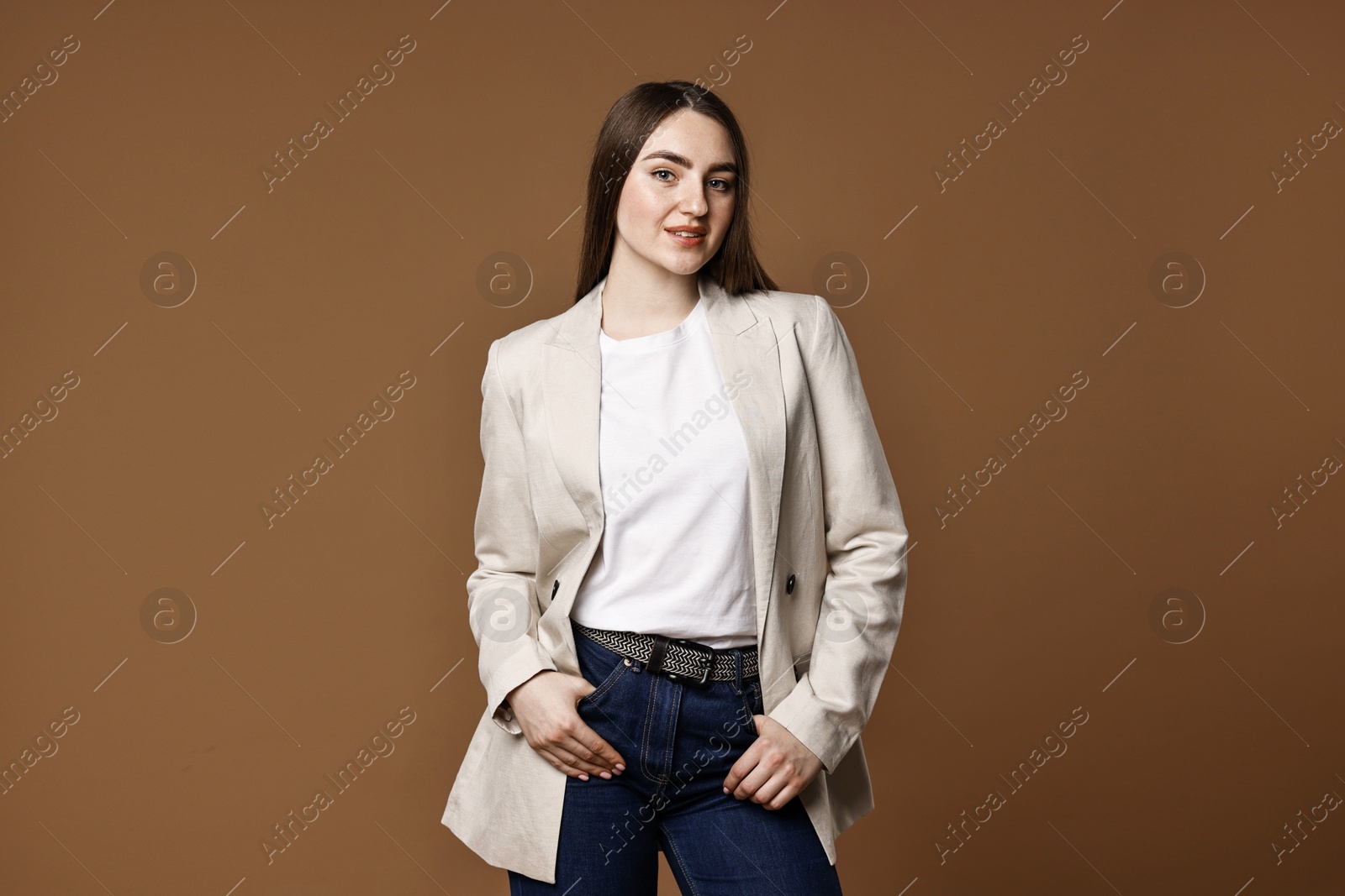 Photo of Beautiful young woman in stylish jeans on brown background