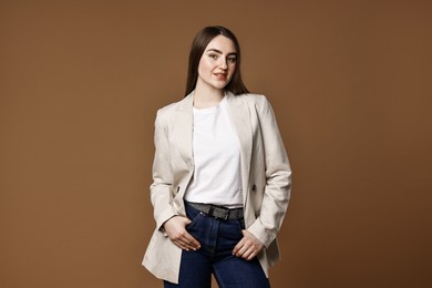 Photo of Beautiful young woman in stylish jeans on brown background