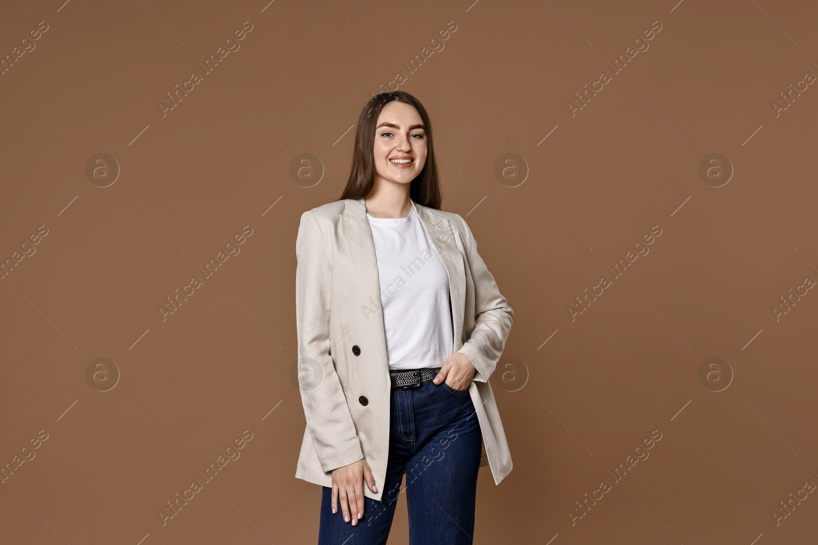 Photo of Smiling woman in stylish jeans on brown background