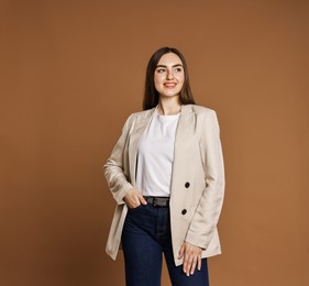 Photo of Smiling woman in stylish jeans on brown background. Space for text