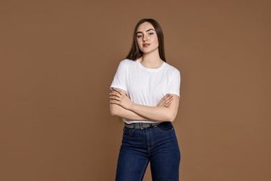 Photo of Beautiful young woman in stylish jeans on brown background