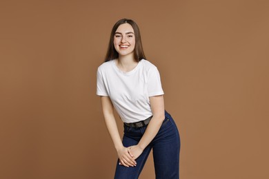 Photo of Smiling woman in stylish jeans on brown background