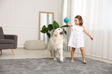 Little girl playing with cute dog at home, space for text