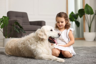 Photo of Little girl with cute dog on carpet at home