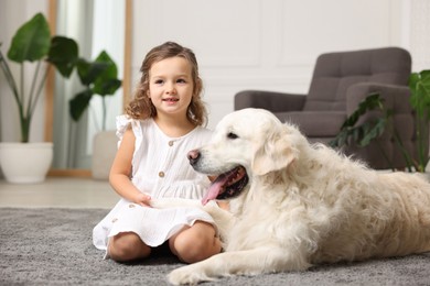 Photo of Little girl with cute dog on carpet at home