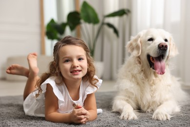 Little girl with cute dog on carpet at home