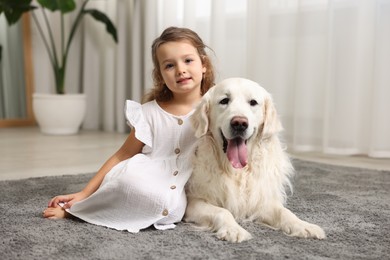 Photo of Little girl with cute dog on carpet at home