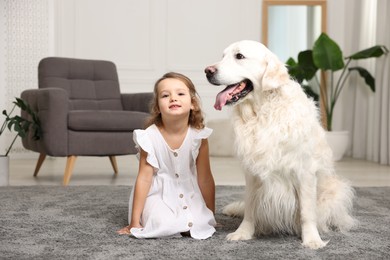 Photo of Little girl with cute dog on carpet at home