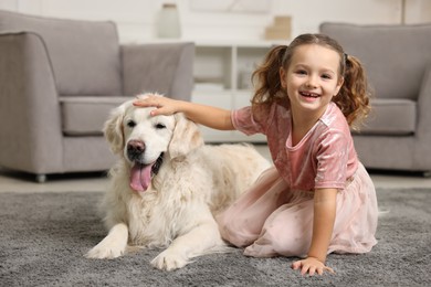 Photo of Little girl with cute dog on carpet at home