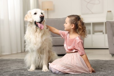 Little girl with cute dog on carpet at home