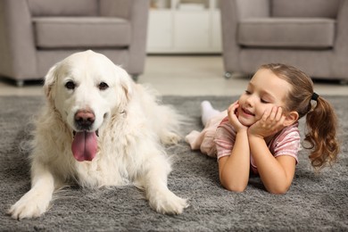 Little girl with cute dog on carpet at home