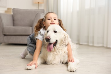 Photo of Little girl with cute dog on floor at home, space for text