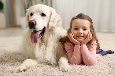 Little girl with cute dog on carpet at home