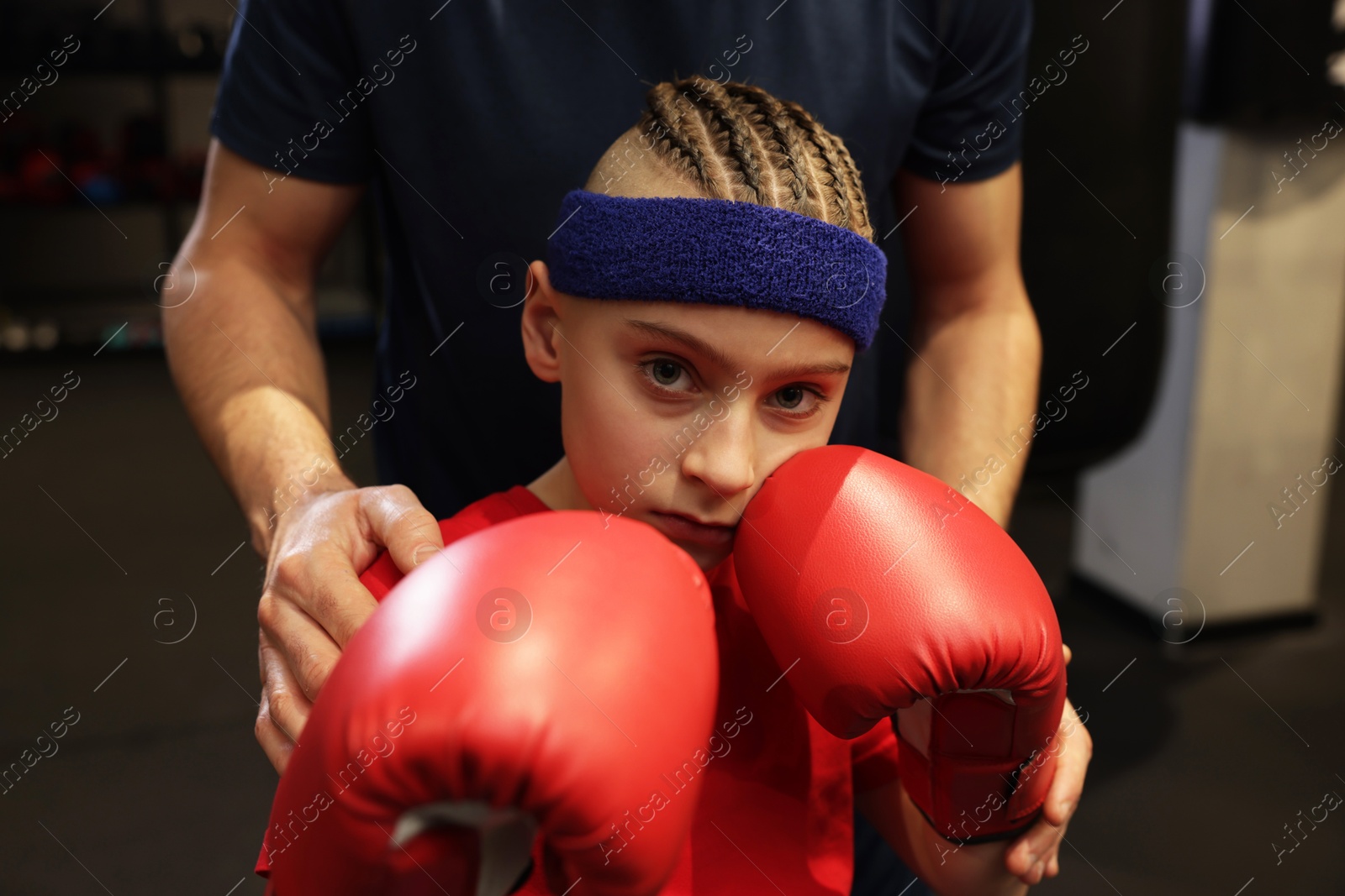 Photo of Boy in protective gloves with his boxing coach at training center