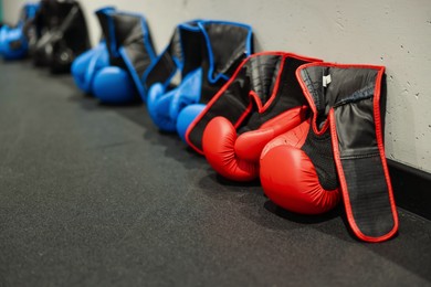 Photo of Different protective boxing gloves near light wall indoors