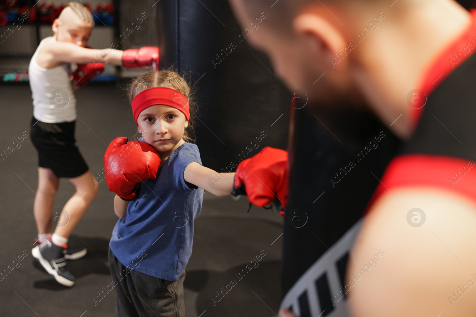 Photo of Children having boxing practice with their coach in training center, selective focus