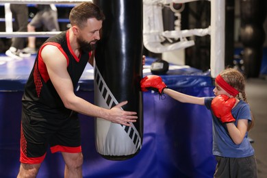 Girl in protective gloves having boxing practice with her coach at training center